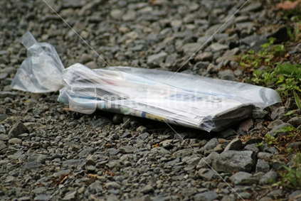 A wrapped newspaper on a metal driveway