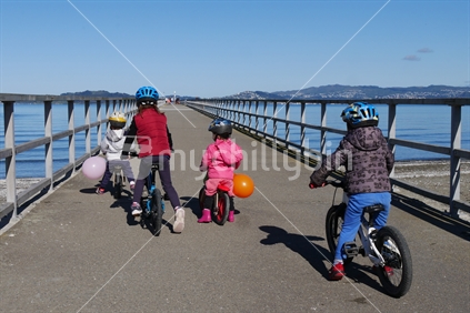 Children riding bikes along a wharf