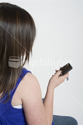 13 year old girl texting on cell phone (phone in focus)