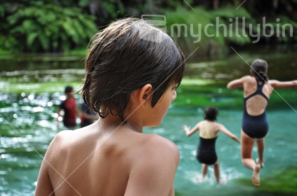A family enjoy the crystal clear waters at Te Waihou natural springs (selective focus and some motion blur)