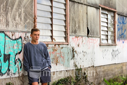 Teenage boy, beside derelict building