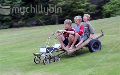 Three brothers racing down a hill in their own home made cart made from an old pram (their mothers when she was a little girl) and an old milk wagon.