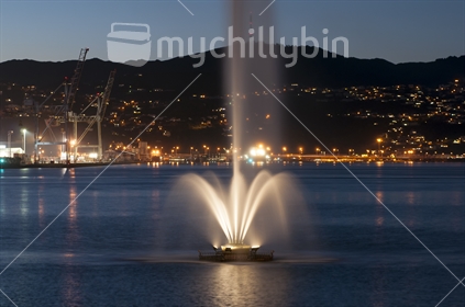 Wellington's Oriental Bay fountain at twilight. Wellington city lights in the distance