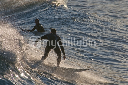 Surfers catch waves in the late afternoon, Wellington's Lyall Bay, New Zealand