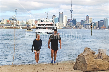 Father and daughter on beach with Auckland ferry and city in background