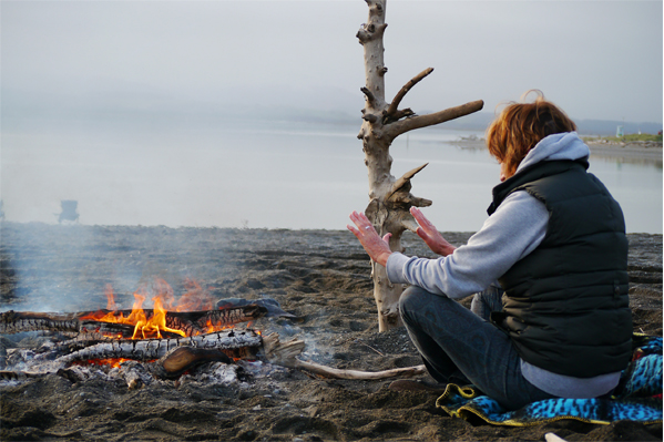 Woman warming hands by fire on the beach mychillybin photo