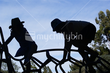 Two children silhouetted on an adventure climbing frame