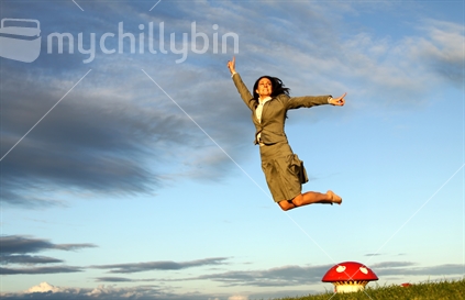 Business woman jumping off ventilator mushroom on Devonport's Mt. Victoria in evening light 