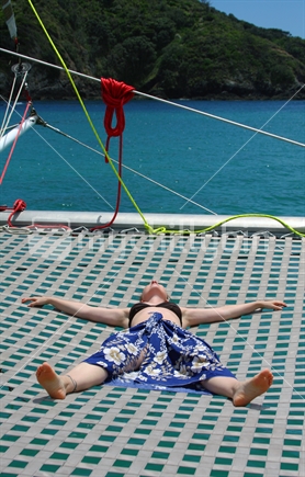 Young woman relaxing at sea, on a catamaran's net