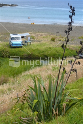 Retro campervan on the edge of beautiful beach in summer, New Zealand