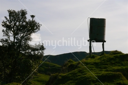 Water tank on new Zealand farm hillside.