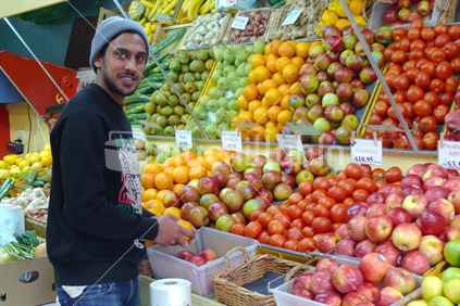 Apples and oranges mirrored in fruit shop with Indian fruit shop owner