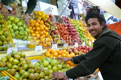 Apples and oranges mirrored in fruitshop with Indian fruit shop owner
