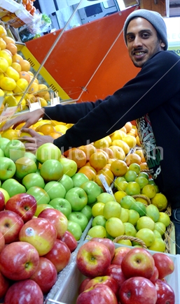 Apples and oranges mirrored in fruit shop with Indian fruit shop owner