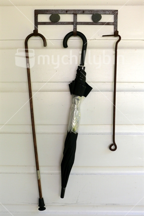Old clothes hook with walking stick, umbrella and fire poker hanging.