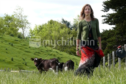 Farming girl wearing gumboots, with cows in the background.