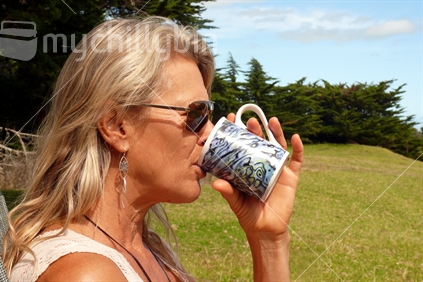 Blond woman drinking coffee from paua printed mug