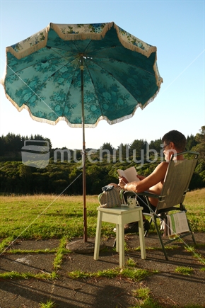 Man sitting under retro umbrella at sunset