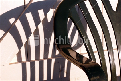 Plastic camping chair with its shadow against wooden bach door