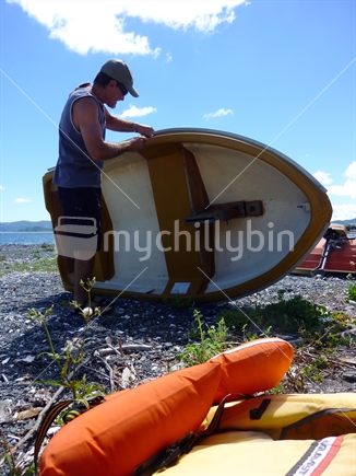 Man preparing dinghy, with life jackets at the ready.