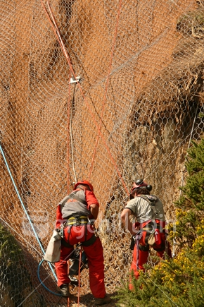 Two workers abseiling a slip on a hill