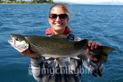 Young woman with a brown trout on Lake Taupo