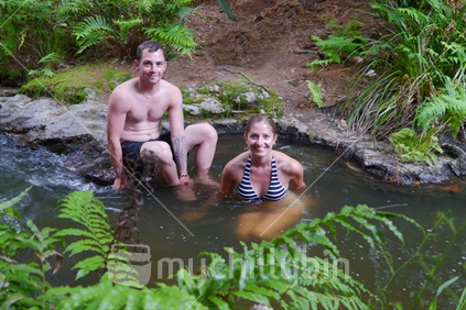 A young couple bathing in the warm Kerosene Creek, Waikato