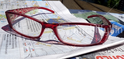Reading glasses resting on newspaper weather report