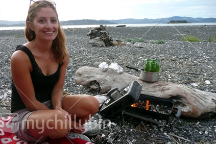 Young woman on beach with coal barbeque