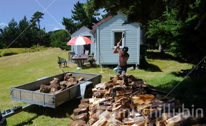 Man chopping wood with family bach in background (selective focus)