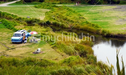 Secluded campsite with retro campervan beside stream