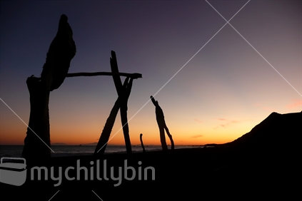Silhouette of a driftwood sculpture at sunset on the beach