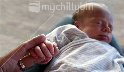Three week old baby holding grandmother's finger