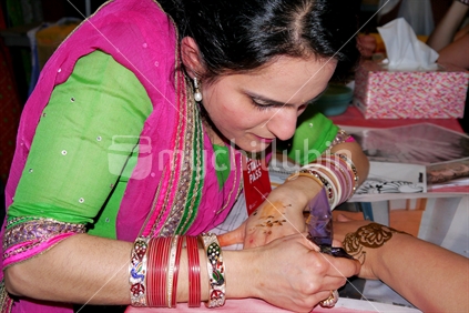 Young woman painting henna pattern onto hand during Diwali