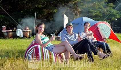 Young adults sitting on beanbags with tent and outdoor bath in background