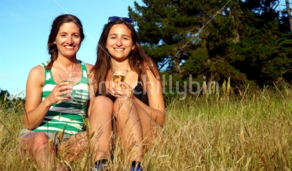 Two young women sitting in tall grass