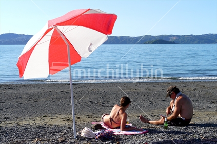 Young woman and father sitting on Eastboune beach, Welington