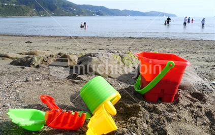 Bucket and spade with people swimming in background