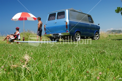 Man and woman relaxing beside retro campervan