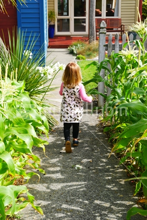 Small child walking down path to house