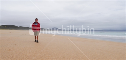 One man walking along beach