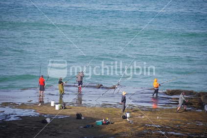 Men fishing of rock in Northland