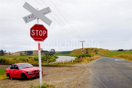 Stop sign at railway crossing with dented car