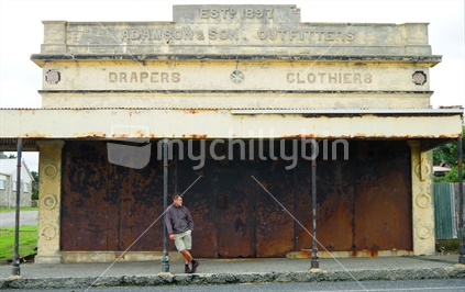 Man standing in front of an old building in the South Island