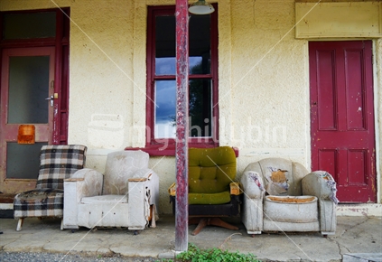 Old couches under veranda of abandoned house