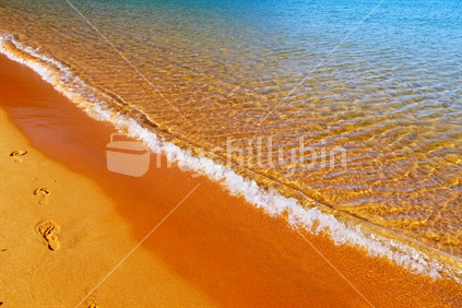 Waves, golden sand and footprints