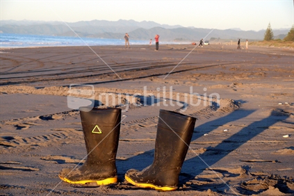Fisherman''s gumboots on the beach in the evening with people on background