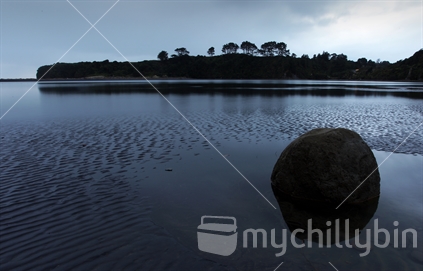A boulder is reflected in the still water of the Tongaporutu River