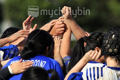 Women rugby players (see blue painted nails) form a huddle during a women's rugby game in Wellington.