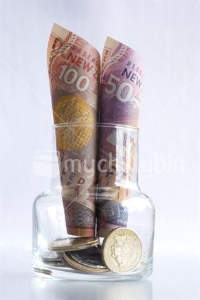 New Zealand currency saved in little glass vase